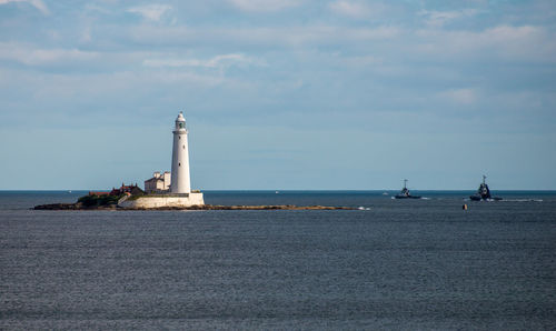 Lighthouse by sea against sky