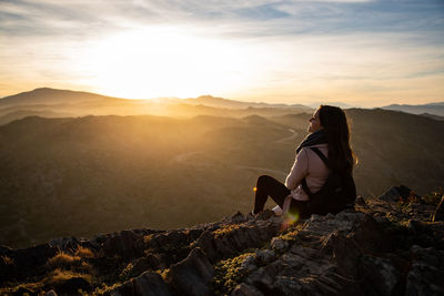 Beautiful women sitting on a rock during sunset on the mountains with copy space