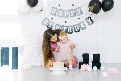 Celebrating the first birthday of a little girl. mom and daughter taste sweet cake in the photo zone