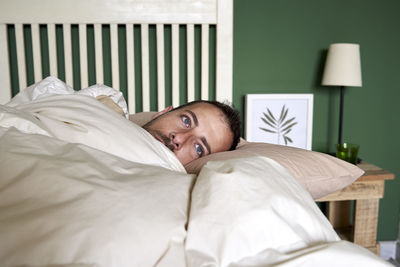 Man contemplating while lying in bed at home