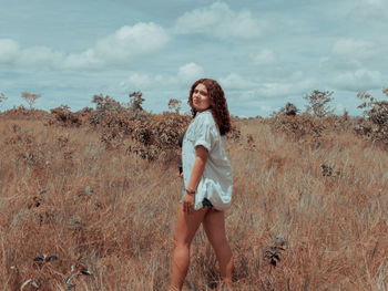 Portrait of smiling young woman standing on land against sky