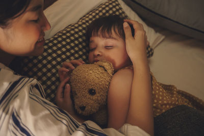 Mother and daughter sleeping on bed at home