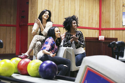 Three young women hanging out at a bowling alley