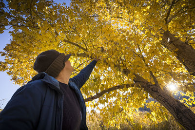 Low angle view of man standing by tree during autumn