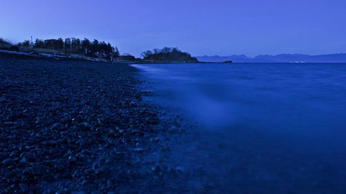 Ocean water misting over the beach rocks at night. 