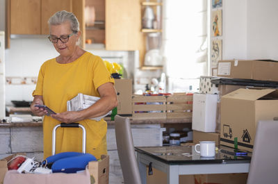 Smiling woman using phone standing at home