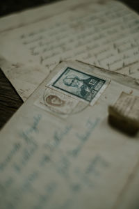 From above shabby aged letters and envelope with postage stamp placed on timber table in dark room