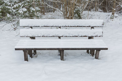 Empty bench on snow covered field during winter