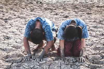 Siblings sitting on cracked land