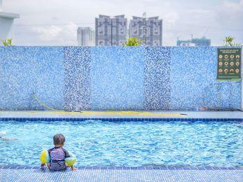 Rear view of boy swimming in pool