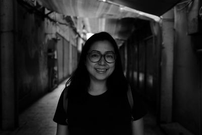 Portrait of young woman standing against wall