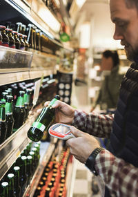 Man using bar code reader on beer bottle in supermarket