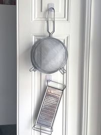 Strainer and grater hanging on window at home