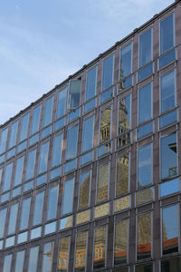 Low angle view of glass building against sky