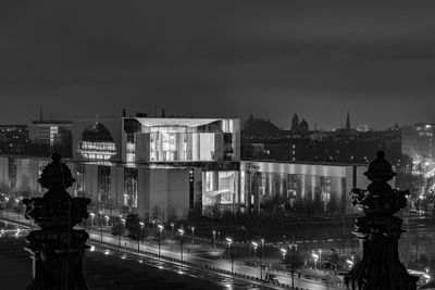 Statue by illuminated city against sky at night