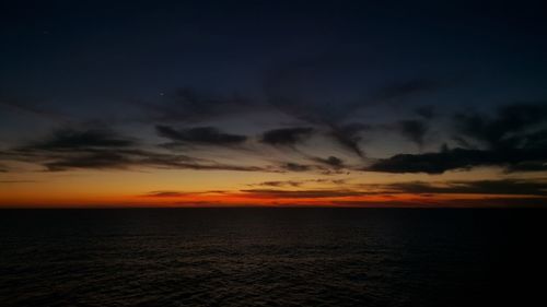 Scenic view of sea against dramatic sky during sunset