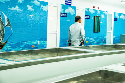 Rear view of man looking at swimming pool