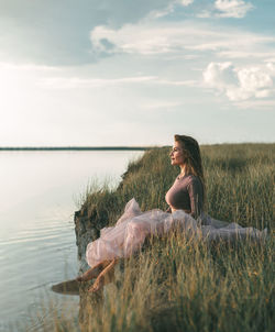 Outdoor recreation. a woman sits on the edge of a cliff near the lake