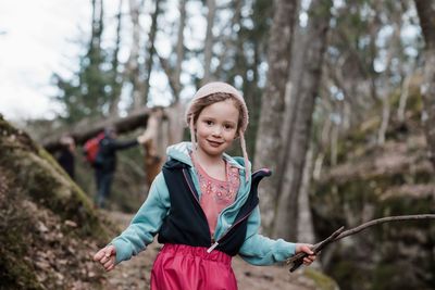Portrait of a young girl holding a stick whilst hiking in sweden