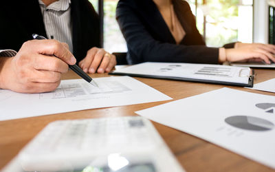 Midsection of man holding paper with text on table