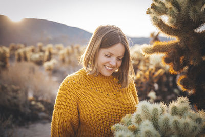 A woman is standing near a cactus in the desert of california