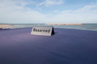 Information sign on beach against sky