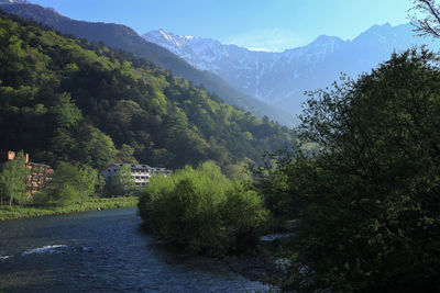 Scenic view of river amidst trees and mountains against sky