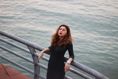 High angle view of woman leaning on railing at observation point against sea