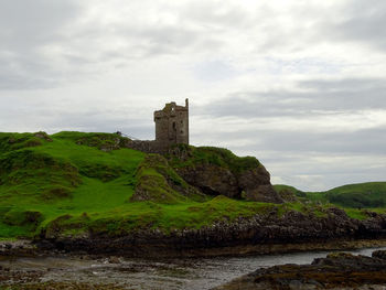 Castle on mountain against cloudy sky