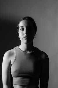 Side view of young woman standing against wall