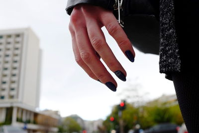 Close-up of hand against sky in city