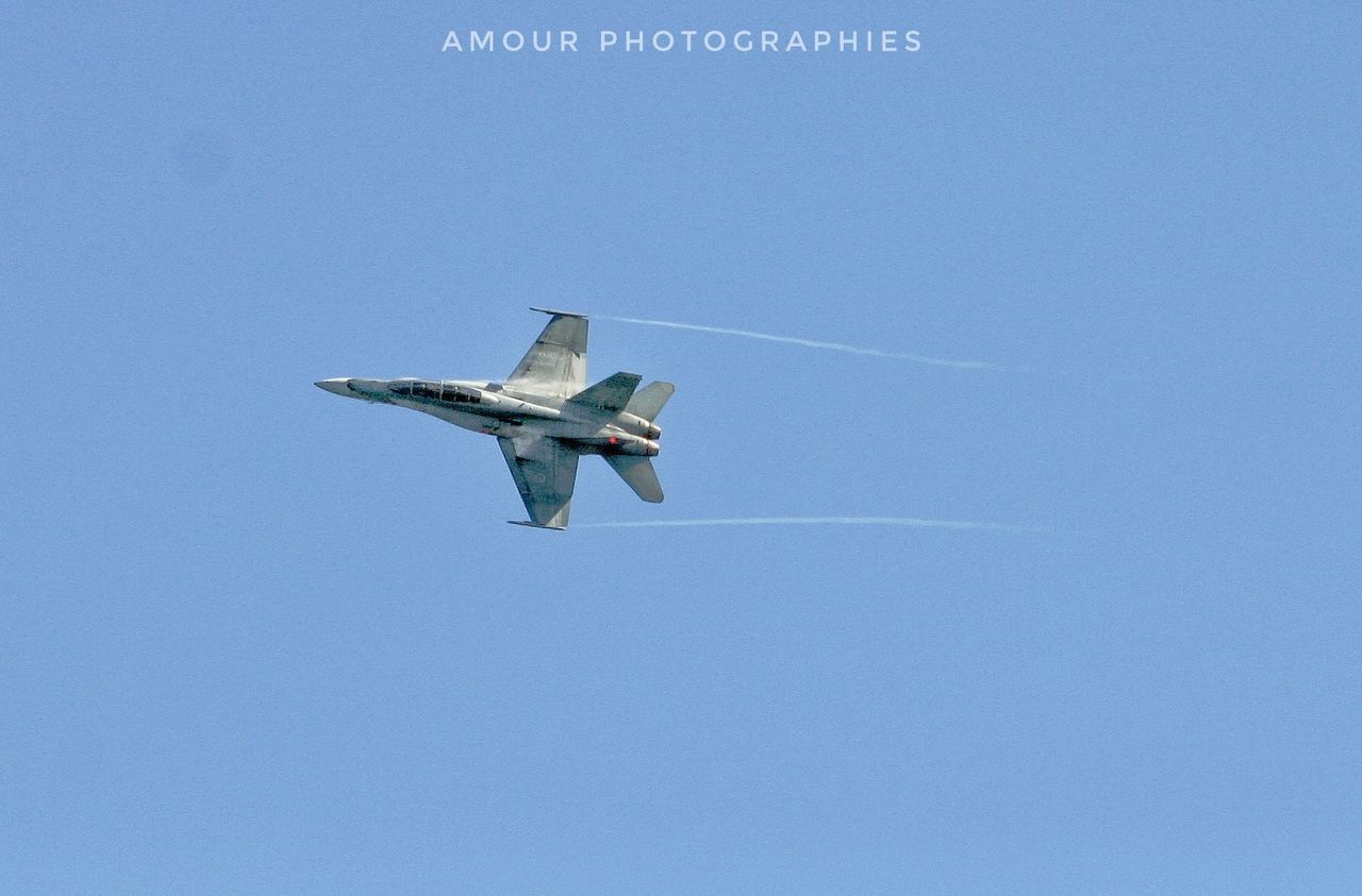 LOW ANGLE VIEW OF AIRPLANE FLYING IN CLEAR BLUE SKY