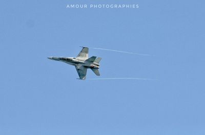 Low angle view of airplane flying against clear blue sky