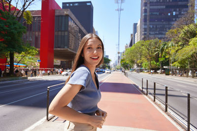 Portrait of young woman standing in city