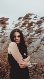 Portrait of beautiful young woman standing next to water