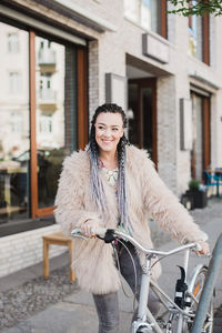 Woman with bicycle standing on sidewalk