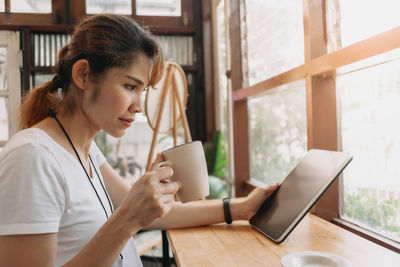 Young woman using mobile phone at table