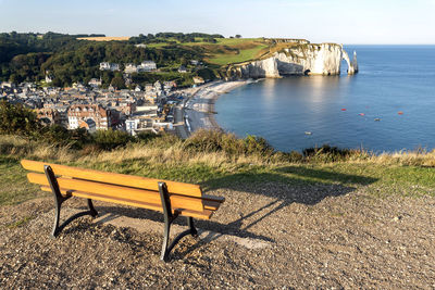 Empty bench by sea against sky