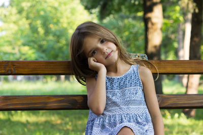 Portrait of smiling girl sitting on bench at park