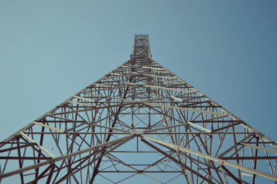 Low angle view of electricity tower against blue sky