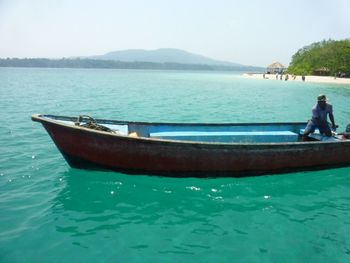 People in boat on sea against clear sky