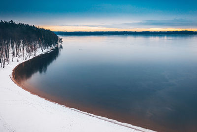 Scenic view of lake against sky during sunset in winter