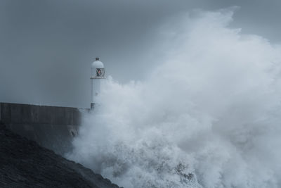 Lighthouse by sea against sky