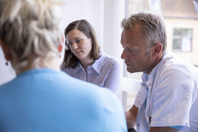 Doctors talking to female patient while sitting in medical clinic