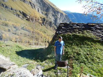 Rear view of man standing on rock against mountain