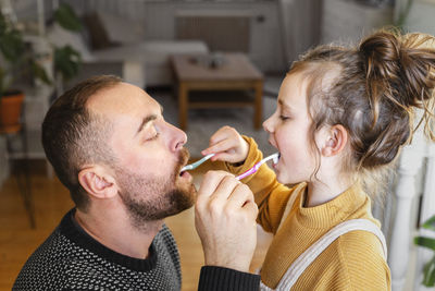 Father and daughter brushing each other teeth