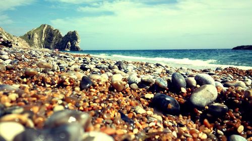 Close-up of pebbles on beach against sky