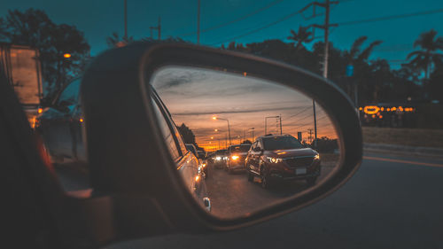 Reflection of cars seen in side-view mirror during sunset