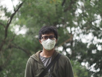 Portrait of man wearing mask while standing against trees