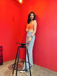 Portrait of young woman standing against yellow wall